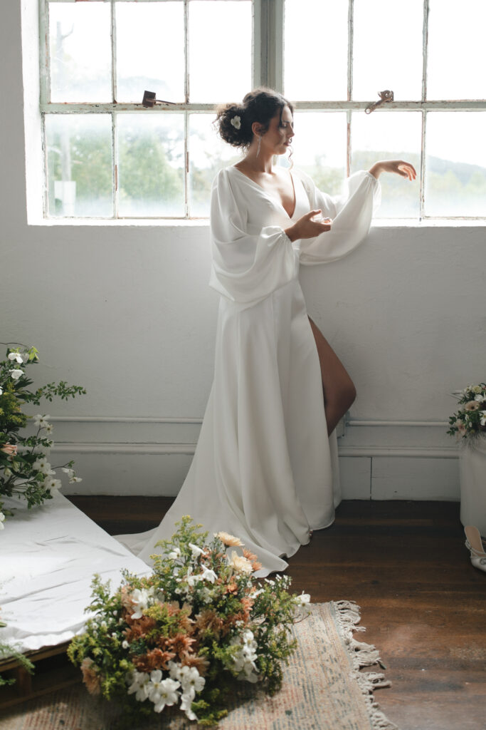 bride posing in front of window at mill studio photographed by asheville wedding photographer